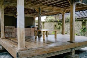 TampaksiringAlvia Joglo House & Private Pool的木甲板上配有桌子的木门廊