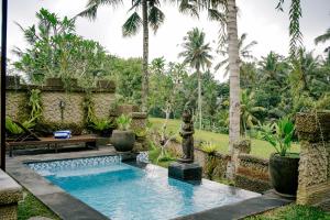 TampaksiringAlvia Joglo House & Private Pool的棕榈树花园中间的游泳池