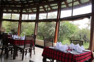 OlolaimutiekMara Empiris Safari Camp的用餐室设有桌椅和窗户。