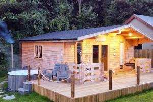 莫维尔Luxury log cabin with wood fired hot tub的小木屋设有甲板和桌子