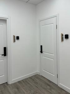 波季Express Inn的两间门位于带白色墙壁和木地板的客房