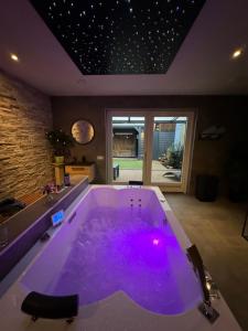 圣安娜兰Bed & Wellness Chinel Luxe vakantiehuis met Sauna's en Bubbelbad的客房内的大浴缸配有紫色照明