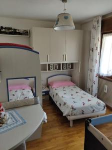 皮耶韦迪卡多雷Appartamento comodo e curato per famiglie的一间卧室设有两张床、一张桌子和一个窗口
