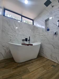 福尔图纳Villa El Bosque Dorado的浴室设有白色浴缸,拥有大理石墙壁。