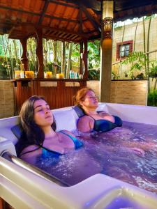 瓜鲁雅Pousada e SPA Canto do Mar的两个妇女在度假村的按摩浴缸里
