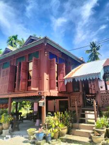 甲抛峇底Homestay Teratak Kayu kota Aur的一座木房子,拥有红色百叶窗和植物
