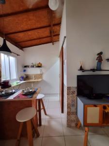 伯迪亚哥Recanto dos Mares - Chalés e suíte - Bertioga-SP-Próximo Sesc的一间厨房,内设桌子和一台电视机