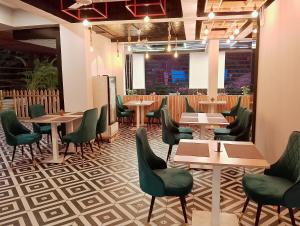 GoaSkon Baga Bliss Hotel by Orion Hotels的餐厅设有木桌和绿色椅子