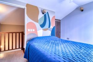 圣保罗Logement 4 pièces Étang St Paul的一间卧室配有一张蓝色的床和色彩缤纷的墙壁