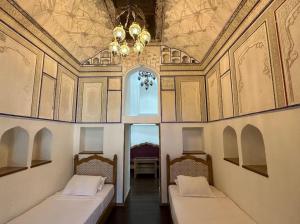 布哈拉Marhaba boutique Madrasah 15th-16th century的配有吊灯的客房内的两张床