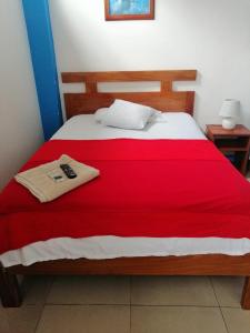 阿约拉港Descanso del Petrel的一张带红色毯子的床和遥控器