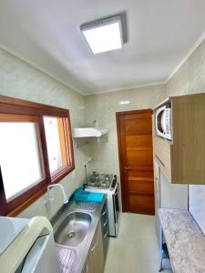 卡庞达卡诺阿Apartamento 2 quadras do mar centro Capão da Canoa的一间带水槽和炉灶的小厨房