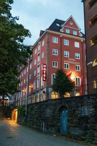 卑尔根罗森克兰茨卑尔根酒店的一座大型的红色建筑靠近石墙