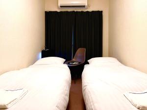 东京Hotel&Co. Sagami的一间设有两张床和椅子的房间