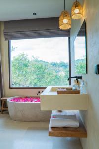 龙目岛库塔Olea Villas Resort的带浴缸的浴室和大窗户