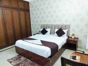 新德里Hotel Soft Petal Residency - Delhi Airport的一间卧室配有一张大床和一个木制橱柜