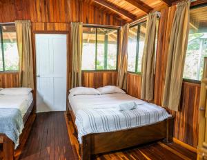希门尼斯港Kalea Yard Hotel的配有木墙和窗户的客房内的两张床