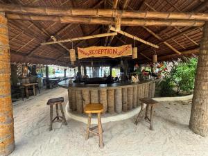 Santa FePili Beach Resort Agmanic的酒吧,带两个凳子和阅读接待的标志