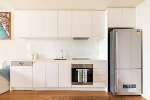 墨尔本Beachside flat with free parking的厨房配有白色橱柜和不锈钢冰箱
