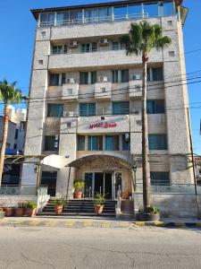 安曼阿哈蒂尔酒店的前面有棕榈树的建筑