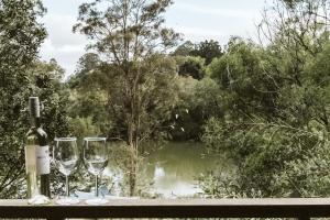 马莱尼"On Burgum Pond" Cottages的两杯酒杯坐在桌子上,享有池塘的景色
