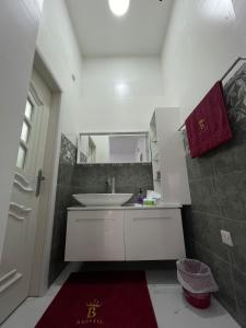 拜尔卡Bareeq Rest House的浴室设有白色水槽和红色地毯。