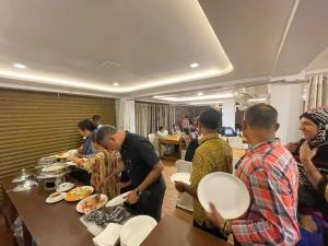 西里古里Hotel Sundaram Palace的一群人站在桌子旁吃着食物