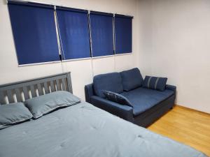 首尔Spacious Master Suite的一间卧室配有一张床和一张蓝色的沙发