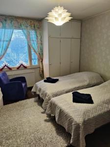 拉赫蒂City Home Lahti的一间卧室配有两张床、一把椅子和一个吊灯。