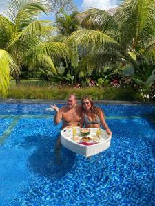乌干沙The Jiwana Bali Resort的坐在游泳池桌子上的男女