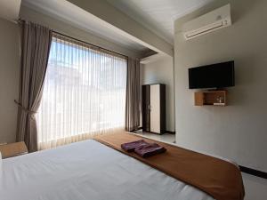 日惹The Cabin Hotel Ngupasan的一间卧室设有一张床和一个大窗户