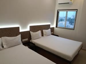 苏拉特Hotel Ritz Vesu - Hotels in Vesu, Surat的小型客房 - 带2张床和窗户