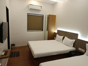 苏拉特Hotel Ritz Vesu - Hotels in Vesu, Surat的酒店客房设有两张床和电视。