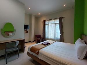 日惹The Cabin Hotel Ngupasan的一间卧室配有一张床、一张书桌和一个窗户。