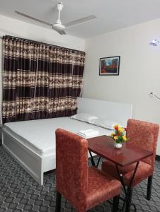 达卡Hotel In Need - Near to the US and Canada Embassy in Dhaka的配有一张床和一张桌子及椅子的房间