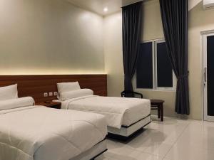 TjolomaduGenio Syariah Hotel Solo的酒店客房设有两张床和窗户。