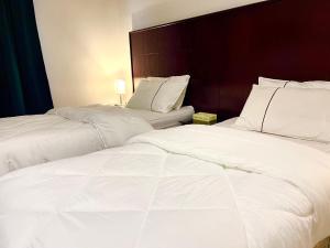 伊尔比德Saraya Al Joude的配有白色床单的酒店客房内的两张床