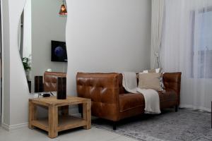 米德兰Urbane- By LaSerene -Carlswald的客厅里一张棕色的皮沙发,配有桌子
