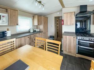 Great ClactonBeautiful 6 Berth Caravan With Decking At Valley Farm Holiday Park Ref 46736v的厨房配有木桌和炉灶。 顶部烤箱