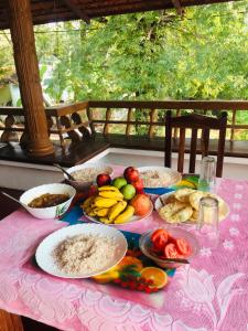 阿勒皮'Marari Johns Homestay' Mararikulam, Alappuzha的一张桌子,上面有盘子,放在粉红色的桌布上