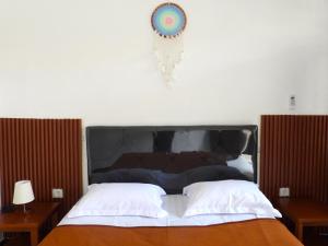 沙努尔Pondok Dete Guesthouse的一张带黑色床头板的床、两张桌子和闹钟