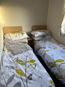 莫克姆Lorraine's Caravan Holiday的两张睡床彼此相邻,位于一个房间里