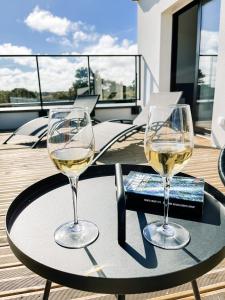 TréveneucVilla Bréhat vue mer et jacuzzi的阳台上的桌子上放着两杯白葡萄酒