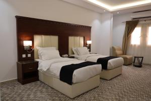 巴哈Al-faleh Hotel的酒店客房,配有两张床和椅子