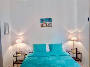 安德诺莱斯贝恩Villa Chez Moun - Plage Betey 5 min的一间卧室配有一张带蓝色床单的床和两盏灯。