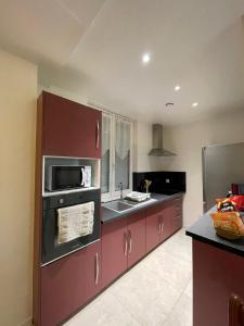 勒芒Au logis du circuit des 24h00的厨房配有紫色橱柜、水槽和微波炉