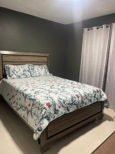 金斯敦New Kingston Retreat的一间卧室配有一张带花卉棉被的床和窗户。