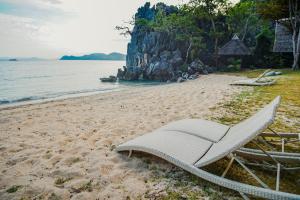 科隆Sangat Island Dive Resort的海滩上的白色躺椅