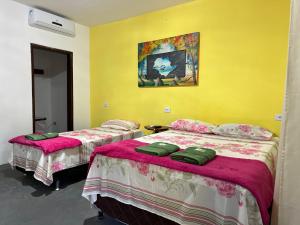 伦索伊斯Encanto do Parque Hospedagem的黄色墙壁客房的两张床