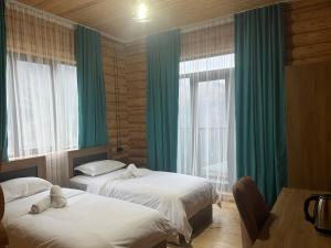 KhuloHotel ANNA PALACE的配有绿窗帘和窗户的客房内的两张床